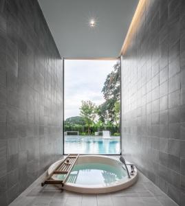 a bath tub in a bathroom with a large window at Riva Vista Riverfront Resort Chiang Rai in Chiang Rai