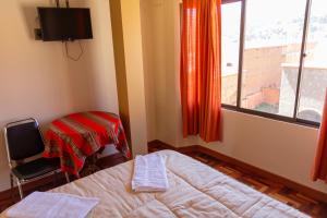 1 dormitorio con cama, ventana y silla en Hostal Sonia en Copacabana