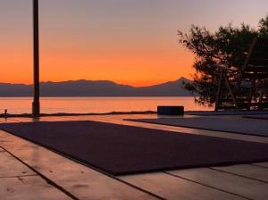 a sunset over a body of water with a tree at Rosys Little Village in Skala