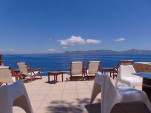 a group of chairs and tables on a patio overlooking the water at Rosys Little Village in Skala