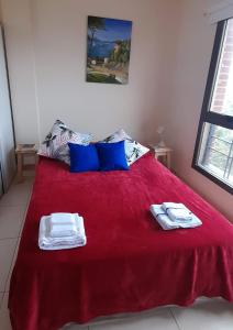 Un dormitorio con una cama roja con toallas. en Monoambiente para descanso o trabajo en Resistencia