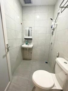 a white bathroom with a toilet and a sink at Garden Inns Motel in Kangar