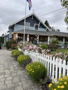 a white fence in front of a house with flowers at The Hazelhouse in Chilliwack