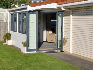 a shed with a door open on a lawn at Our Raglan Town House in Raglan