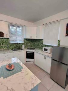 a kitchen with white cabinets and a stainless steel refrigerator at Chalet Belizomi Tropical Villas Studio Villa #3 in Gros Islet