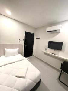 a bedroom with a white bed and a flat screen tv at Garden Inns Motel in Kangar