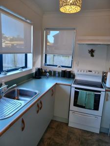 a kitchen with a sink and a stove at Our Raglan Town House in Raglan