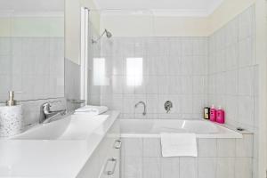 uma casa de banho branca com uma banheira e um lavatório em Stylish and Spacious Launceston Villa + Free Wifi em Launceston