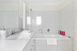 a white bathroom with a tub and a sink at Stylish and Spacious Launceston Villa + Free Wifi in Launceston