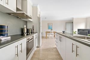 uma cozinha com armários brancos e bancadas pretas em Stylish and Spacious Launceston Villa + Free Wifi em Launceston