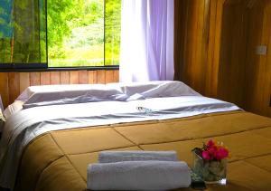 een bed in een kamer met handdoeken en een raam bij Kusi Lodge in Oxapampa