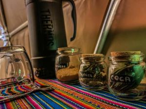 a table topped with glass jars and a coffee maker at Pacucha Glamping in Andahuaylas