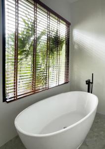 baño con bañera blanca y ventana en Infinity Villa en Salad Beach