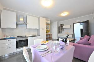a kitchen and living room with a table and purple chairs at Case Mistretta in Altavilla Milicia