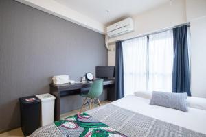 ein Schlafzimmer mit einem Bett und einem Schreibtisch mit einem Computer in der Unterkunft Escort Haruyoshi in Fukuoka