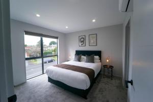 a bedroom with a large bed and a large window at Modern Sunnyhills Town House in Auckland