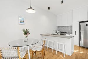 uma cozinha branca com mesa e cadeiras em NEWLY RENOVATED LARGE 3.5 BDRM HOUSE! BEST OF MELB em Melbourne