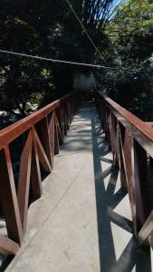 a wooden bridge over a walkway in a park at Hospedaje El Encanto in Minca