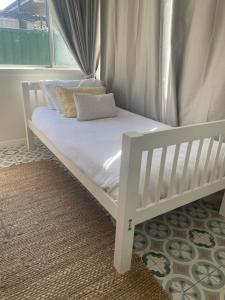- un lit bébé blanc dans une chambre avec fenêtre dans l'établissement Beach shack!, à Sydney