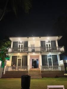 a large white house with a balcony at night at Ocean Breeze Villa in Galle