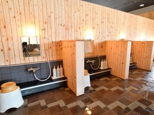 a bathroom with wooden walls and a row of toilets at Oyado Kinkiyu in Teshikaga