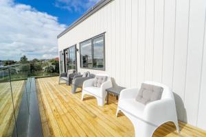 un grupo de sillas blancas en una terraza de madera en Sunnyhills Viewside Town House en Auckland
