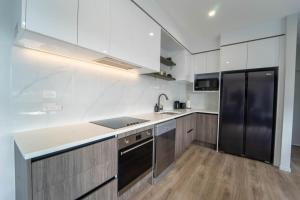 cocina con armarios blancos y nevera negra en Sunnyhills Viewside Town House en Auckland