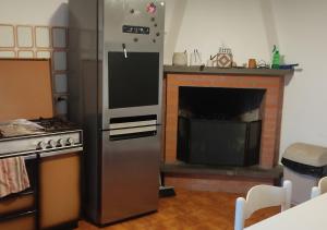 a kitchen with a stainless steel refrigerator and a fireplace at Casa Con Vista Panoramica a Cerreto di Cagli - Animali Ammessi in Pianello
