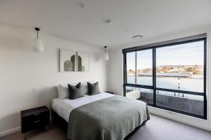1 dormitorio con cama y ventana grande en Little Island Apartments, en Hobart