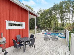 eine Terrasse mit einem Tisch und Stühlen neben einem roten Gebäude in der Unterkunft Holiday home NISSAFORS 