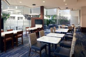 ein Restaurant mit Tischen, Stühlen und Fenstern in der Unterkunft Courtyard by Marriott Los Angeles LAX / Century Boulevard in Los Angeles