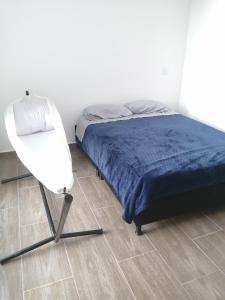 a bedroom with a bed and a white chair at Apartamento Eje Cafetero in Armenia