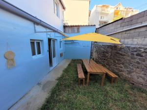 une table en bois avec un parapluie jaune à côté d'un bâtiment dans l'établissement KAZANVIL, à Saint-Denis