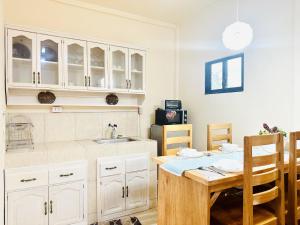 a kitchen with white cabinets and a wooden table at Sunrise Guest House in Taytay
