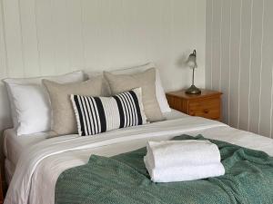 a white bed with a pile of towels on it at Sandpiper - charming beach villa in Port Fairy