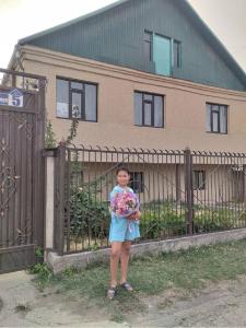 una joven parada frente a una valla con flores en Welcome Guest House, en Tokmok