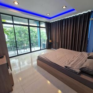 sypialnia z dużym łóżkiem i dużymi oknami w obiekcie Noc House w mieście Bang Khlo