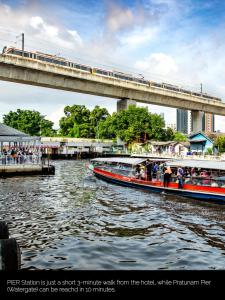 a train on a bridge over a river with two boats at NASA BANGKOK - Airport Rail Link Ramkhamhang in Bangkok