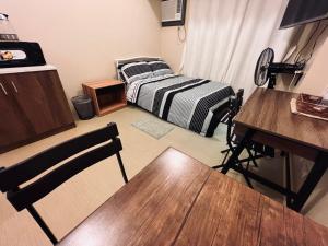 a room with a bed and a table and a desk at C Comfortable Avida Room in Iloilo City