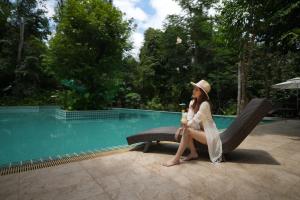 a woman sitting on a chair next to a pool at Nampien Yorla Pa in Ban Nôn