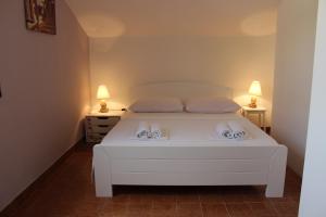 a bedroom with a white bed with two lamps at Apartments Petrada in Omiš