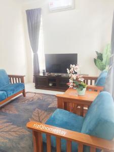 a living room with two chairs and a television at RizQ Homestay Tg Malim in Kerling