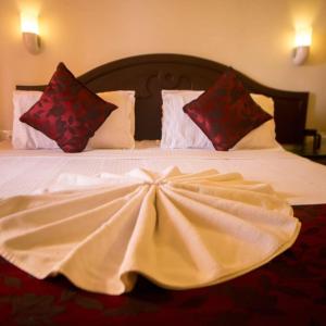 a large white bed with red pillows on it at Hawah Beach Resort Kovalom in Kovalam