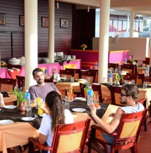 a group of people sitting at tables in a restaurant at Hawah Beach Resort Kovalom in Kovalam