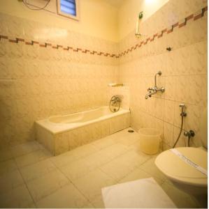 a bathroom with a tub and a toilet and a sink at Hawah Beach Resort Kovalom in Kovalam