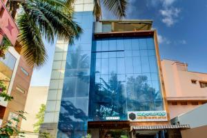 een hoog glazen gebouw met palmbomen ervoor bij Townhouse Oak JVH hotel (Next to Mysore Road Metro Station) in Bangalore