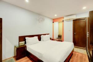 een slaapkamer met een groot wit bed met een houten hoofdeinde bij Townhouse Oak JVH hotel (Next to Mysore Road Metro Station) in Bangalore