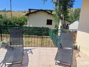dwa krzesła siedzące na patio z płotem w obiekcie Maison de vacances au cœur de la Cerdagne w mieście Angoustrine