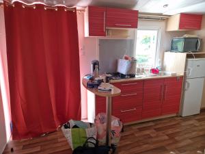 a kitchen with a red curtain and a small table at Camping le ried B021 et N038 in Boofzheim