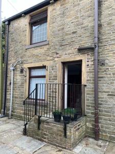 a brick building with a balcony and two windows at Park cottage High Crompton in Shaw